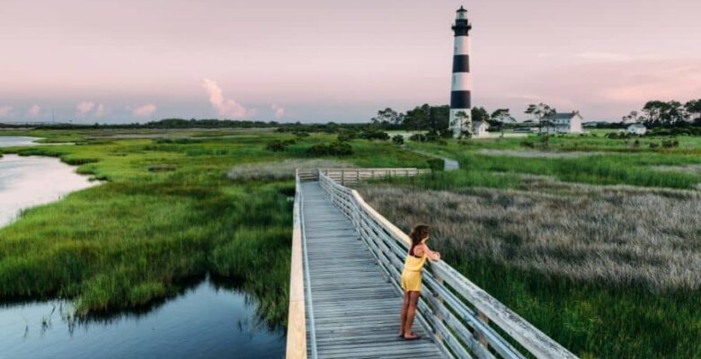 girl in yellow outfit on boardwalk with lighthouse Outer Banks NC