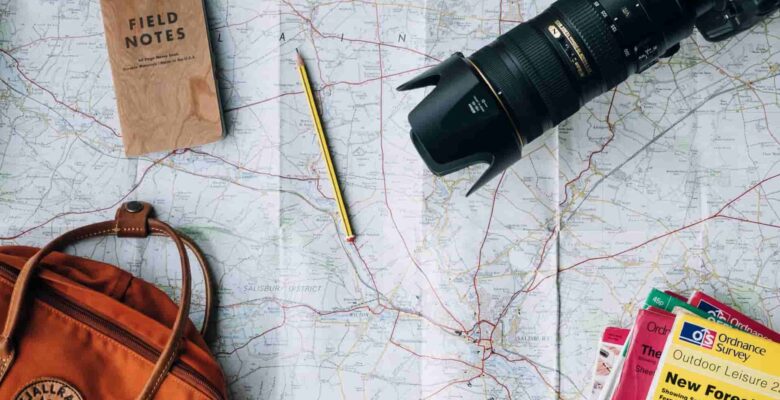 map with travel items like bag, passport, binoculars and books