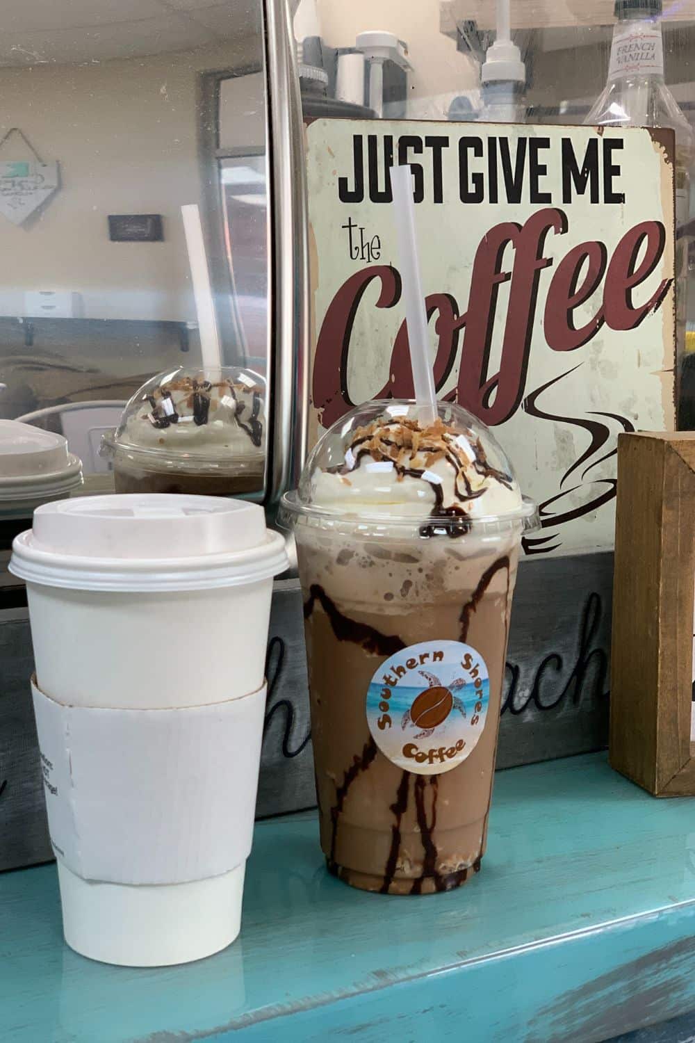 bushwacker frappe with cup of coffee in front of sign at Southern Shores