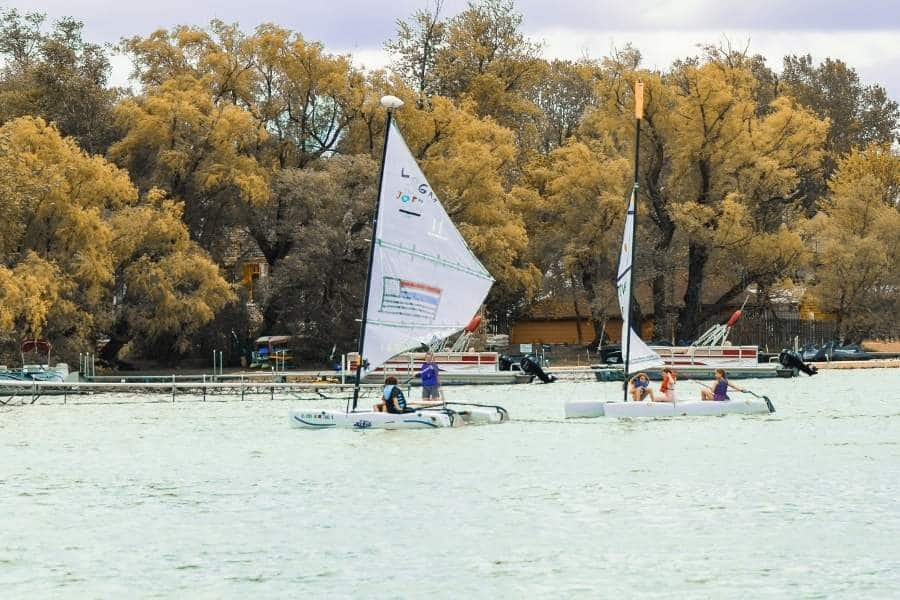 people on sailboats on elkhart lake wi with trees in background