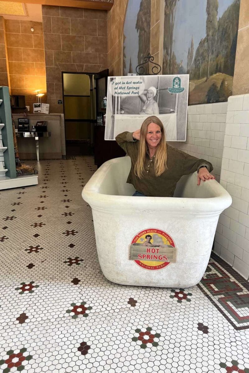 woman sitting in historic bath tub display at hot springs national park