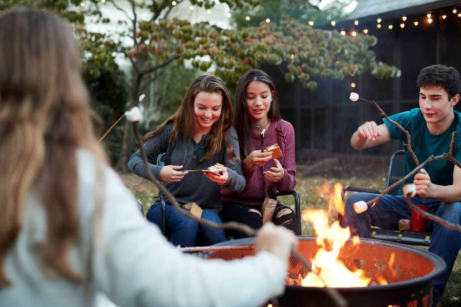 teens roasting marshmallows around a fire pit