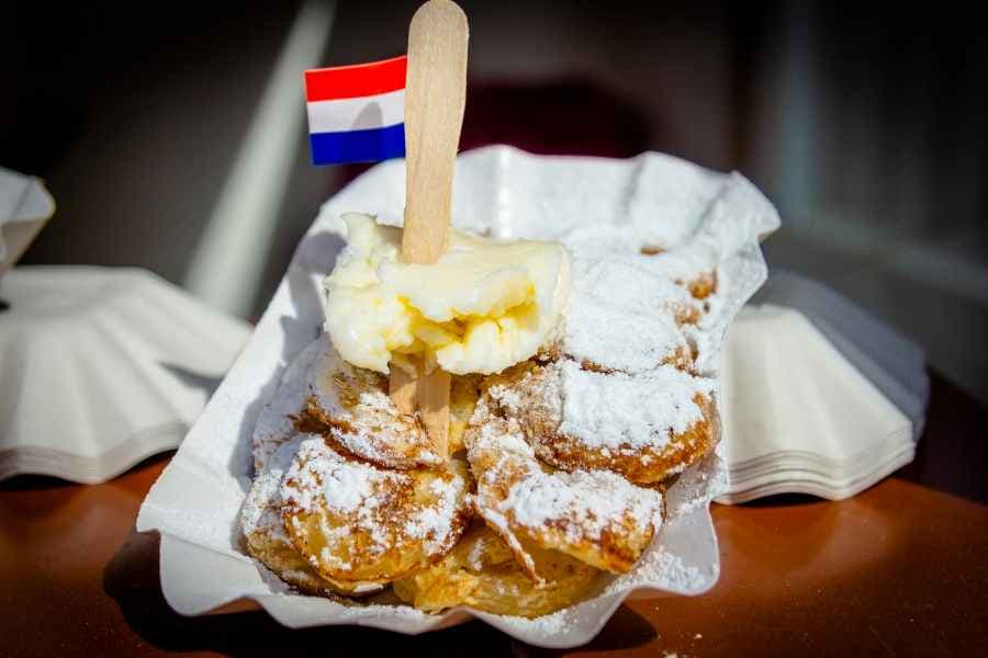 pofferjes sprinkled with sugar and a dutch flag protruding from the middle of the stack