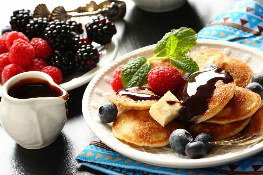 breakfast platter with berries and sprigs of mint on poffertjes