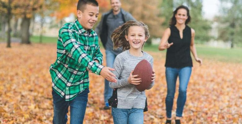 family playing football in fall leaves