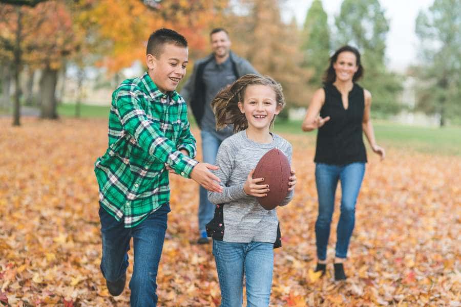 family playing football in fall leaves