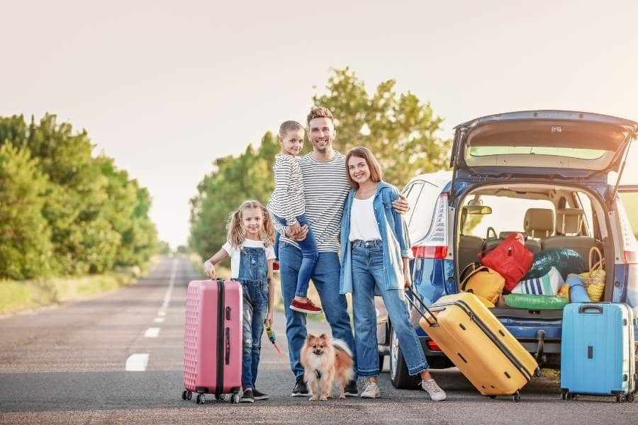 family beside open car with dogs and kids for road trip