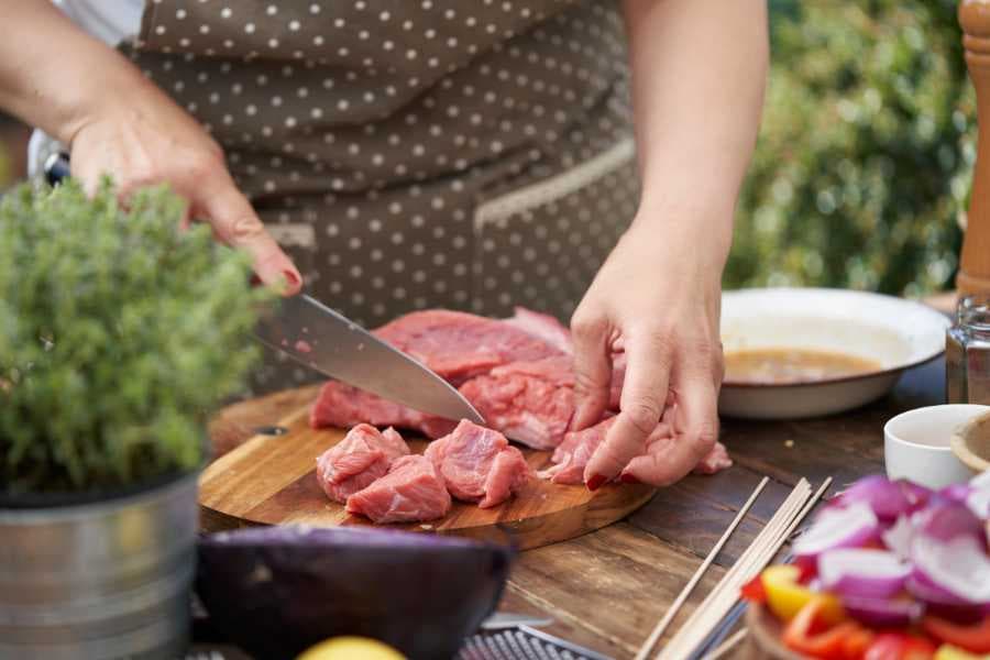 woman with sharp knife cutting beef for kebabs