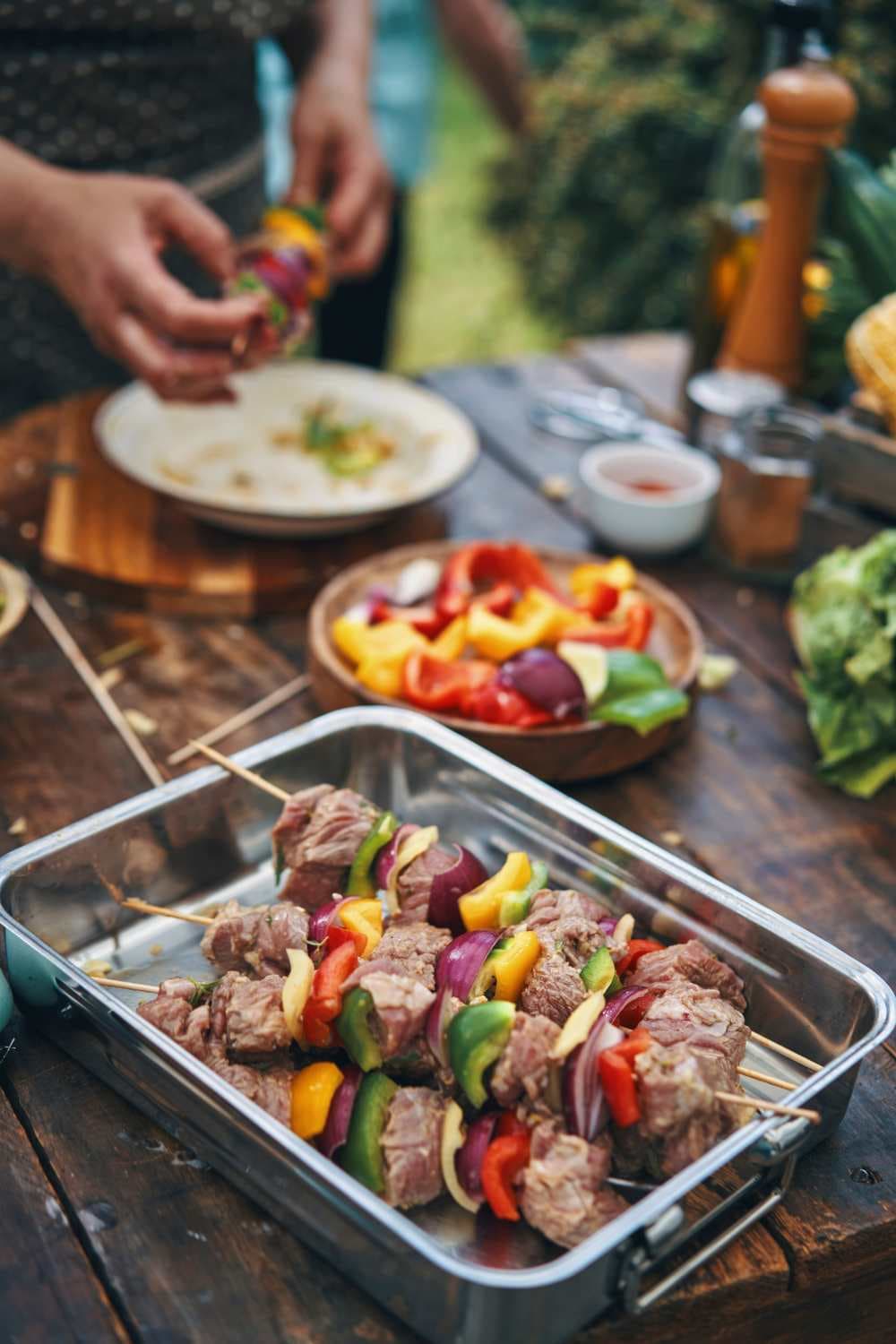 table with pan of beef shish kebobs on wooden skewers