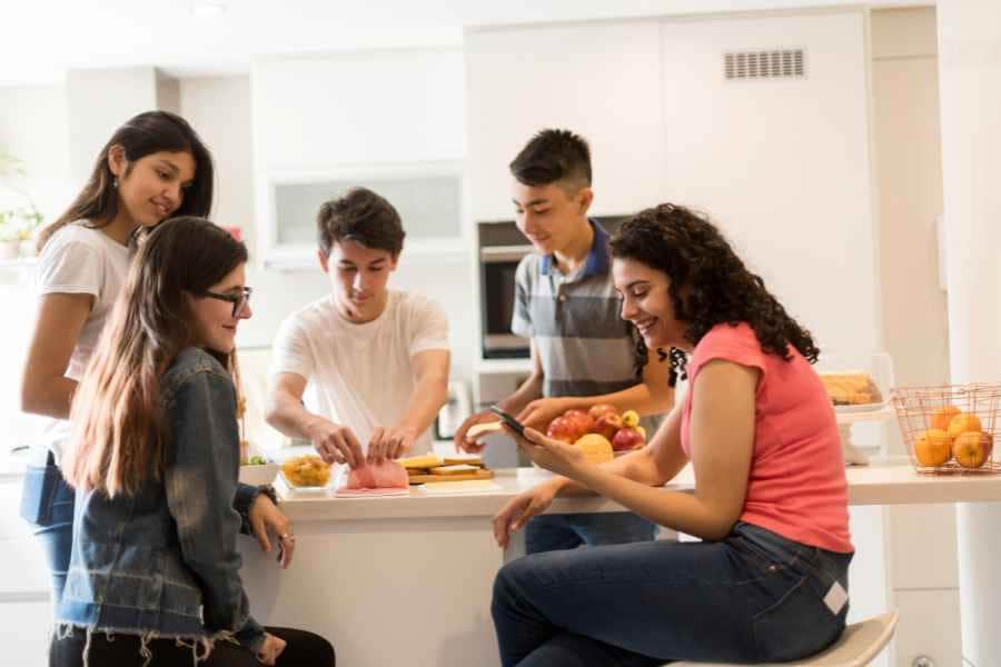 teen with friends at a countertop baking a new recipe