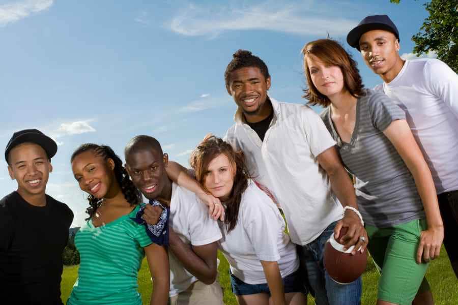 group of teenaged boy and girls having a backyard football game