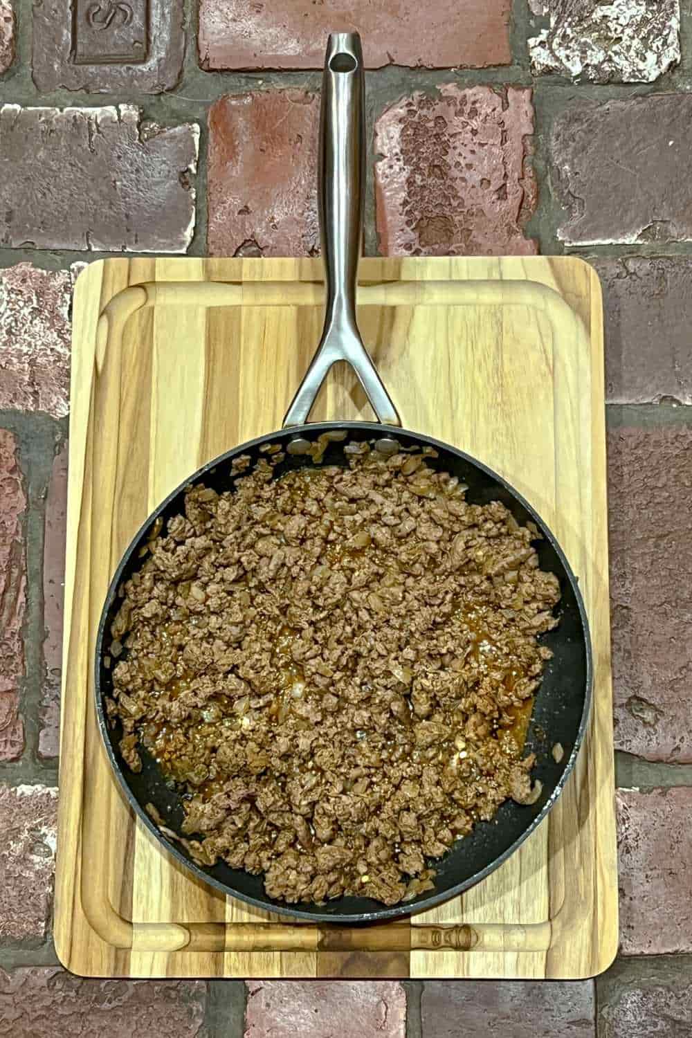 homemade taco meat with seasoning in skillet on wooden cutting board
