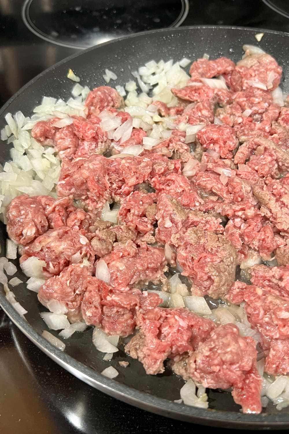 ground beef and onions in skillet starting to brown for tacos
