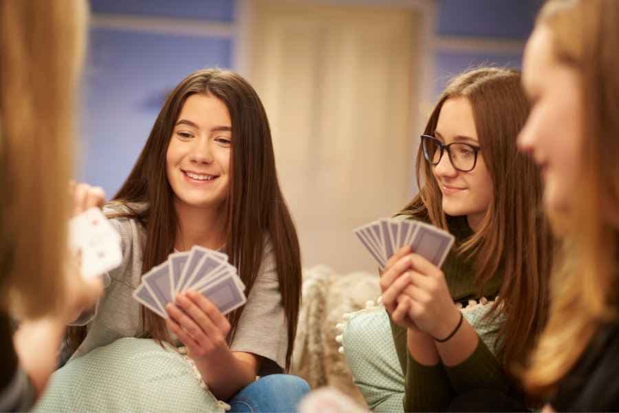 teenage girls playing card games with their friends at home