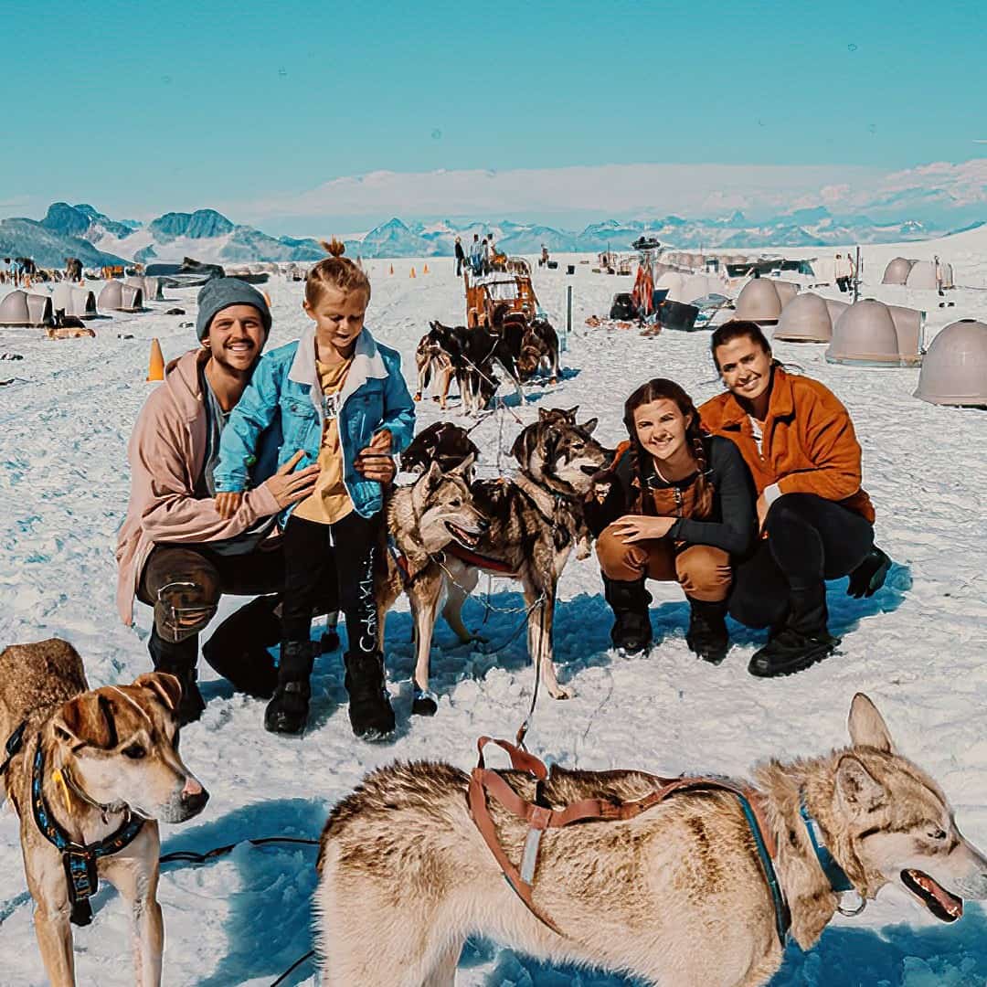 family taking picture with sled dogs in snow