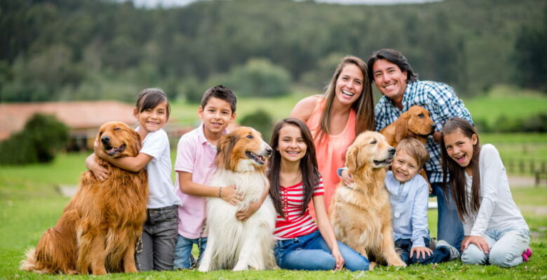 family sitting on grass with their dogs