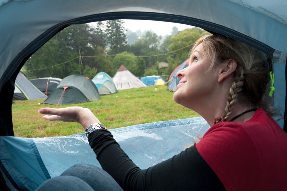 woman checking for rain while inside tent