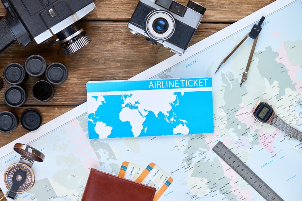 map with airline ticket on top, camera equipment
