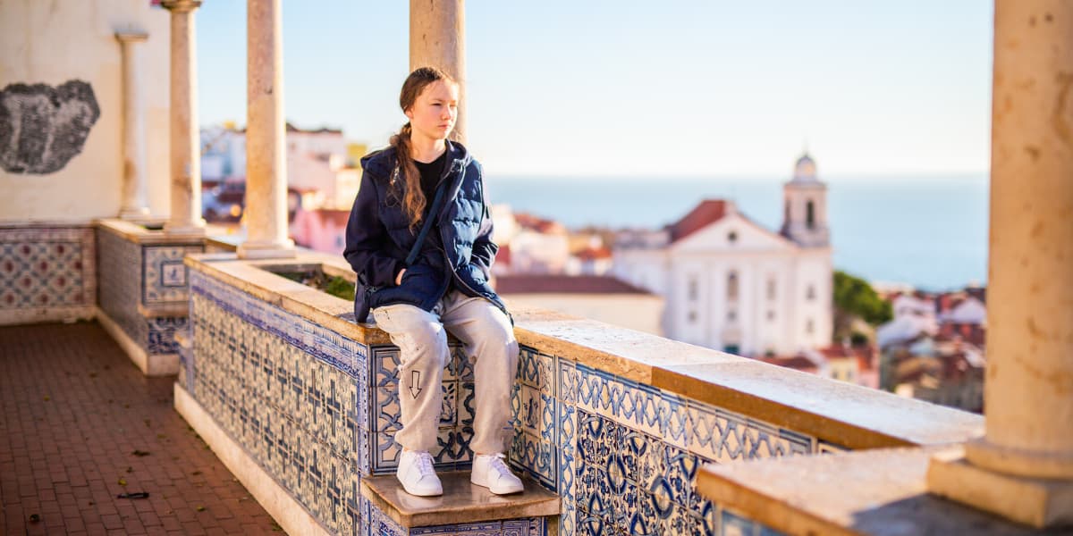 Teenage girl sitting on mosaic wall in Lisbon