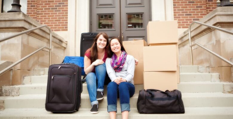 two college freshman moving into residence hall with luggage and boxes