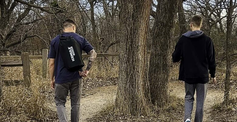boys walking in woods with one having a cooler backpack on back