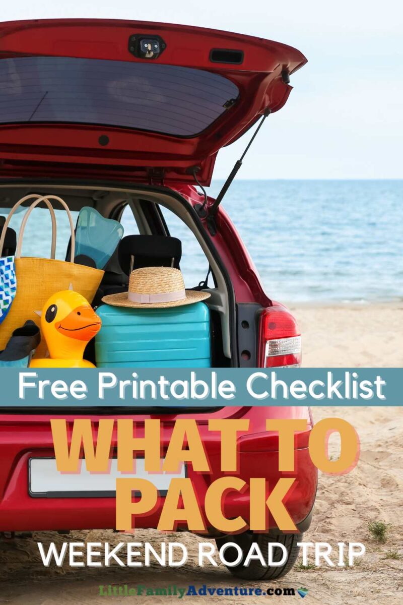 red car parked on sandy beach with tailgate open and lots of bags and floaties packed in back