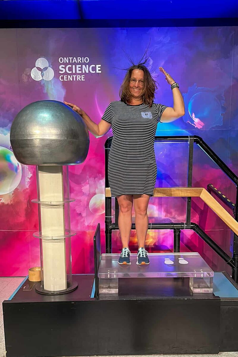 woman touching the Ontario Science Center's Van de Graaff Generator and having her stand on end