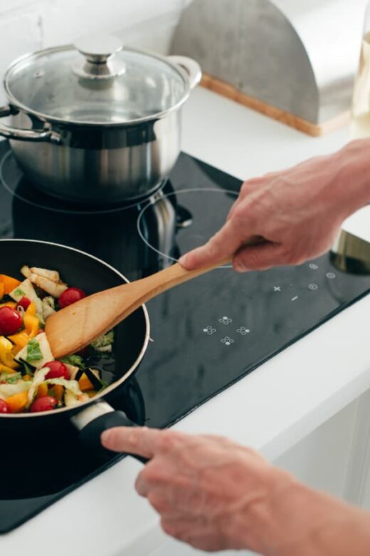cook sauteeing vegetables in stove top pan