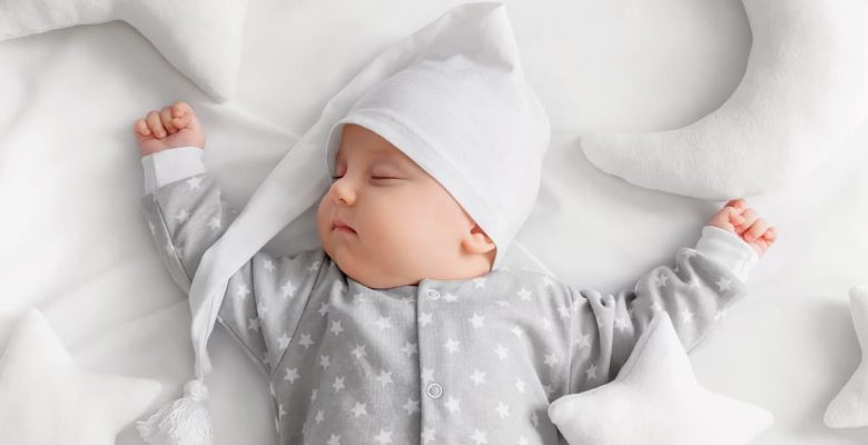 sleeping baby in nightcap wth moon and star pillows