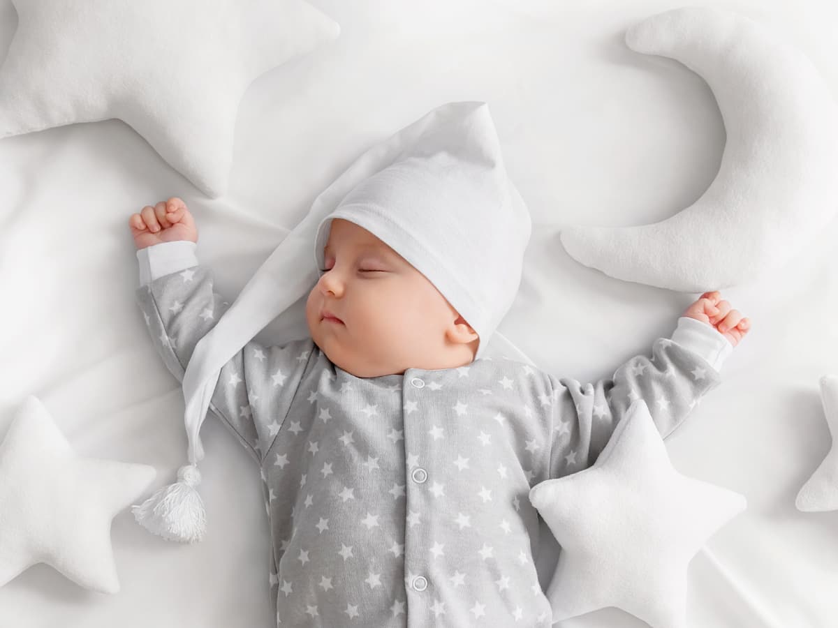 sleeping baby in nightcap wth moon and star pillows