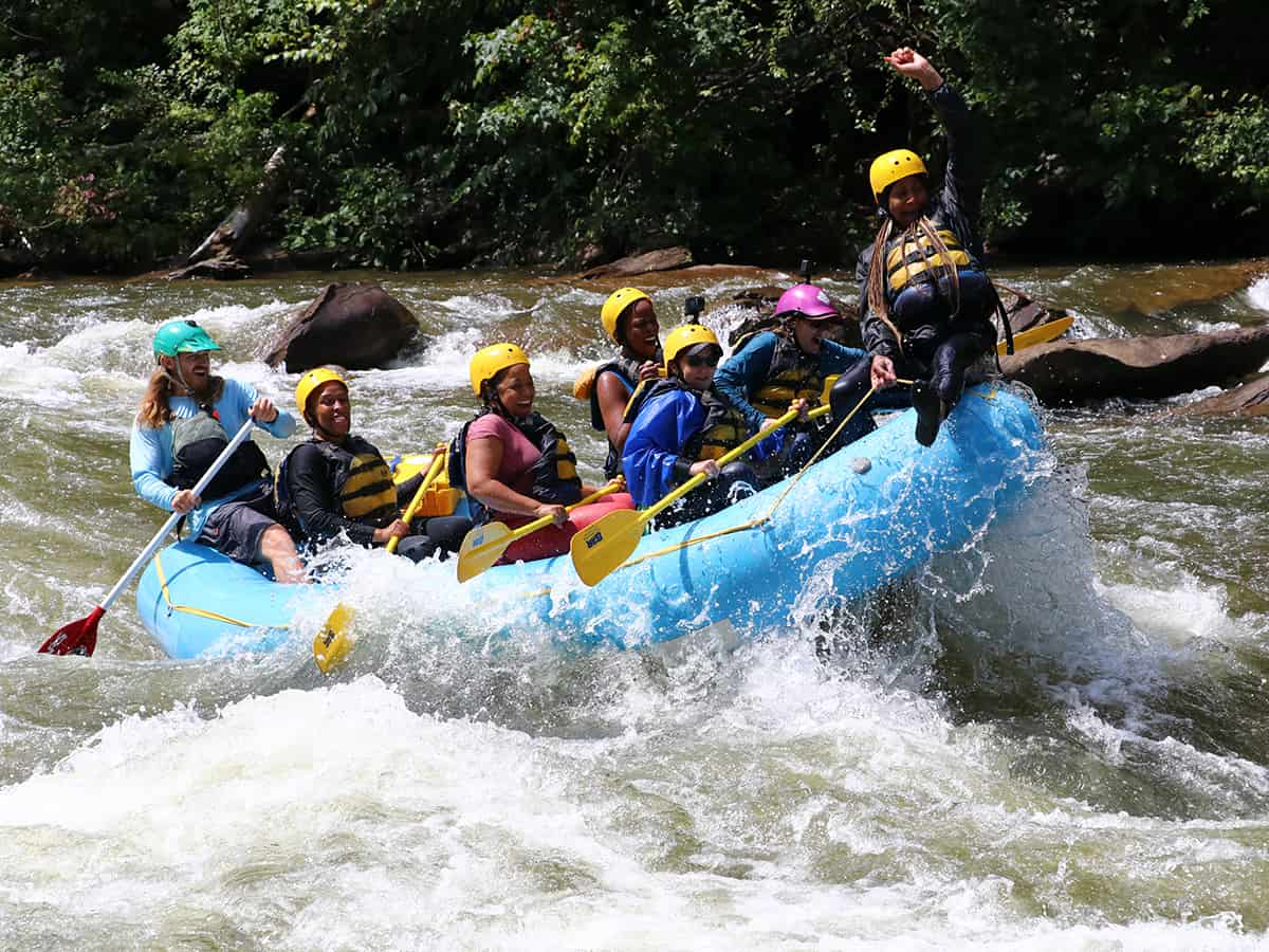 women rafting and one on bow of raft having a great time