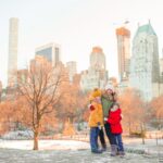 family posing for photo in winter coats with city skyline behind