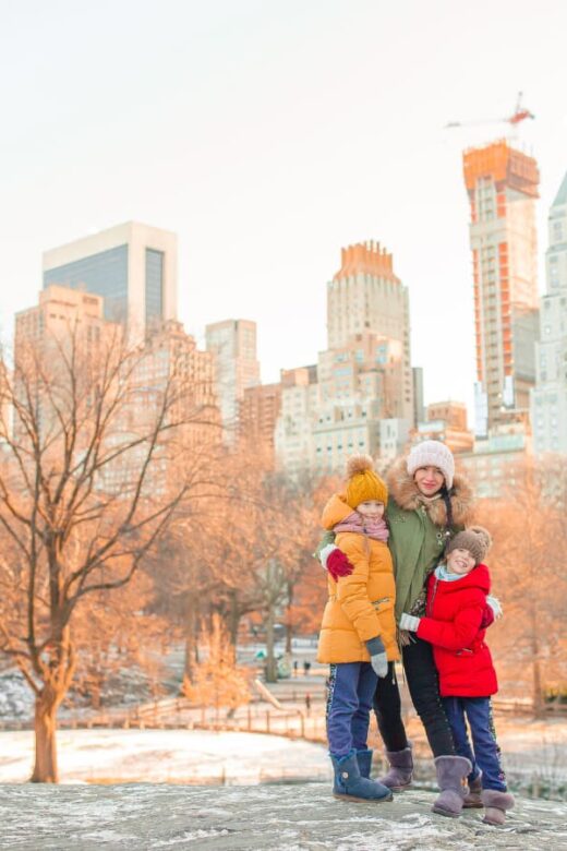 family posing for photo in winter coats with city skyline behind