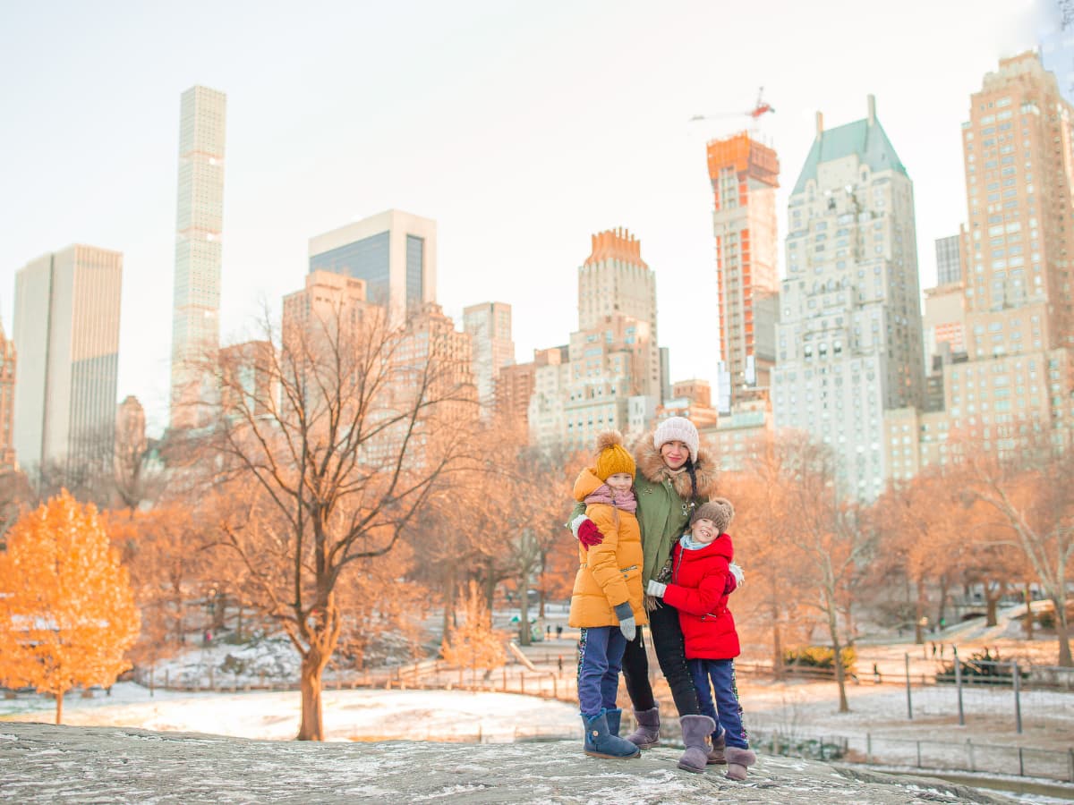 family posing for photo in winter coats with city skyline behind