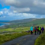 Group of hikers on gravel path with sea view in the distance