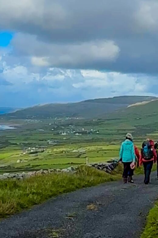 Group of hikers on gravel path with sea view in the distance
