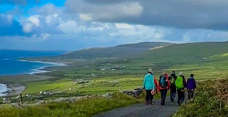 Group of hikers on gravel path with sea view in the distance