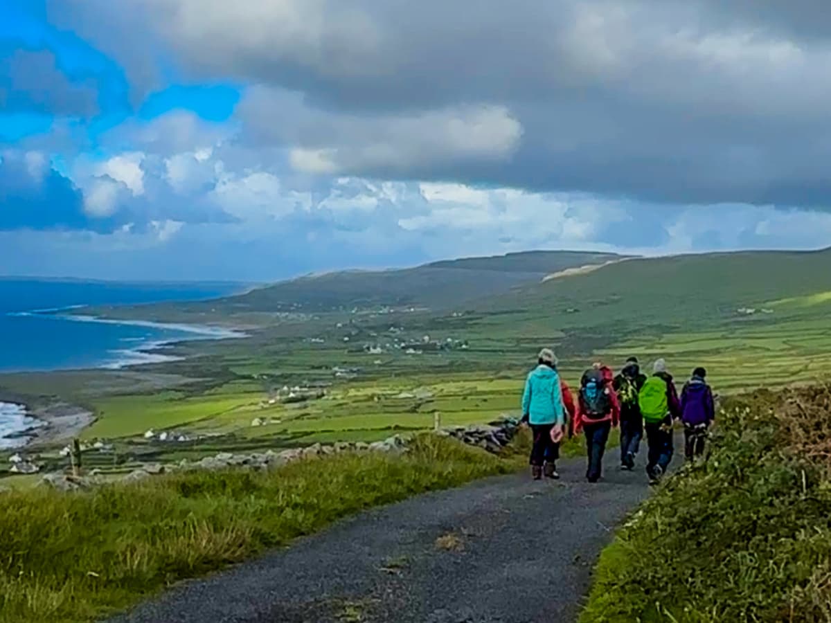 Group of hikers on gravel path with sea view in the distance