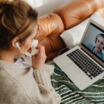 woman on couch looking at laptop and woman on screen