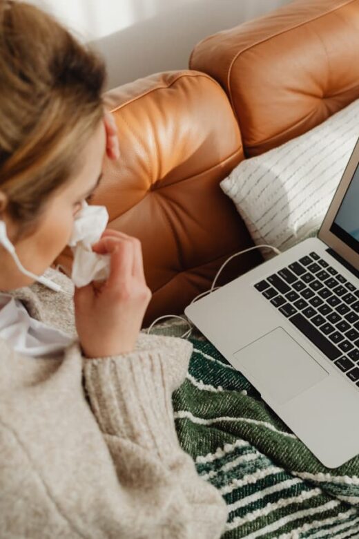 woman on couch looking at laptop and woman on screen
