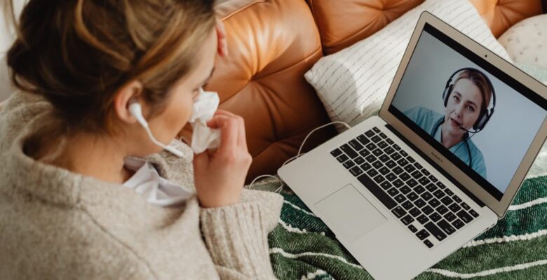 woman on couch looking at laptop and woman on screen