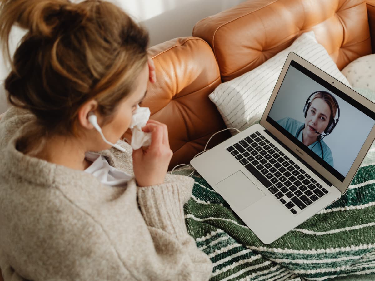 woman on couch looking at laptop and woman on screen