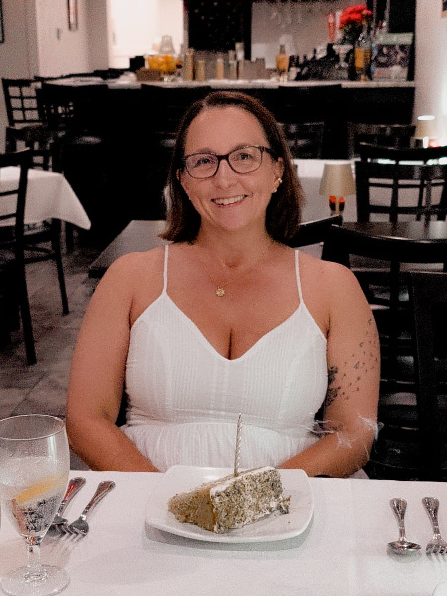 woman smiling in front of birthday cake