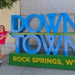 downtown rock springs sign with woman leaning on it