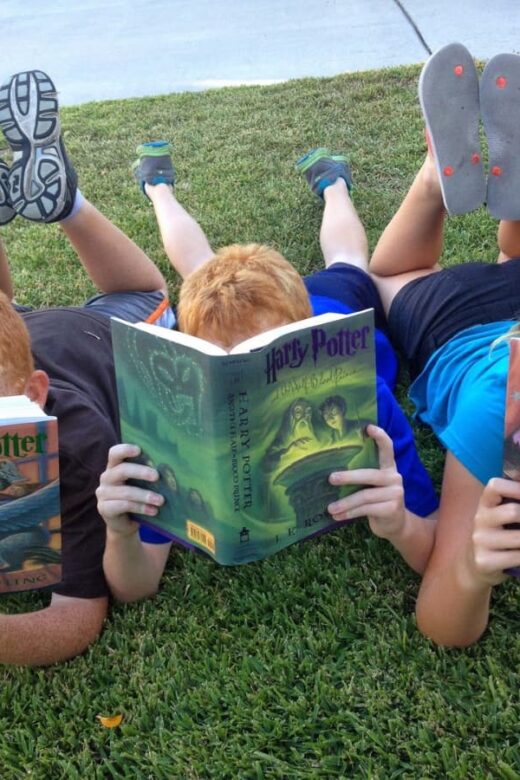 boys reading outdoors on the grass